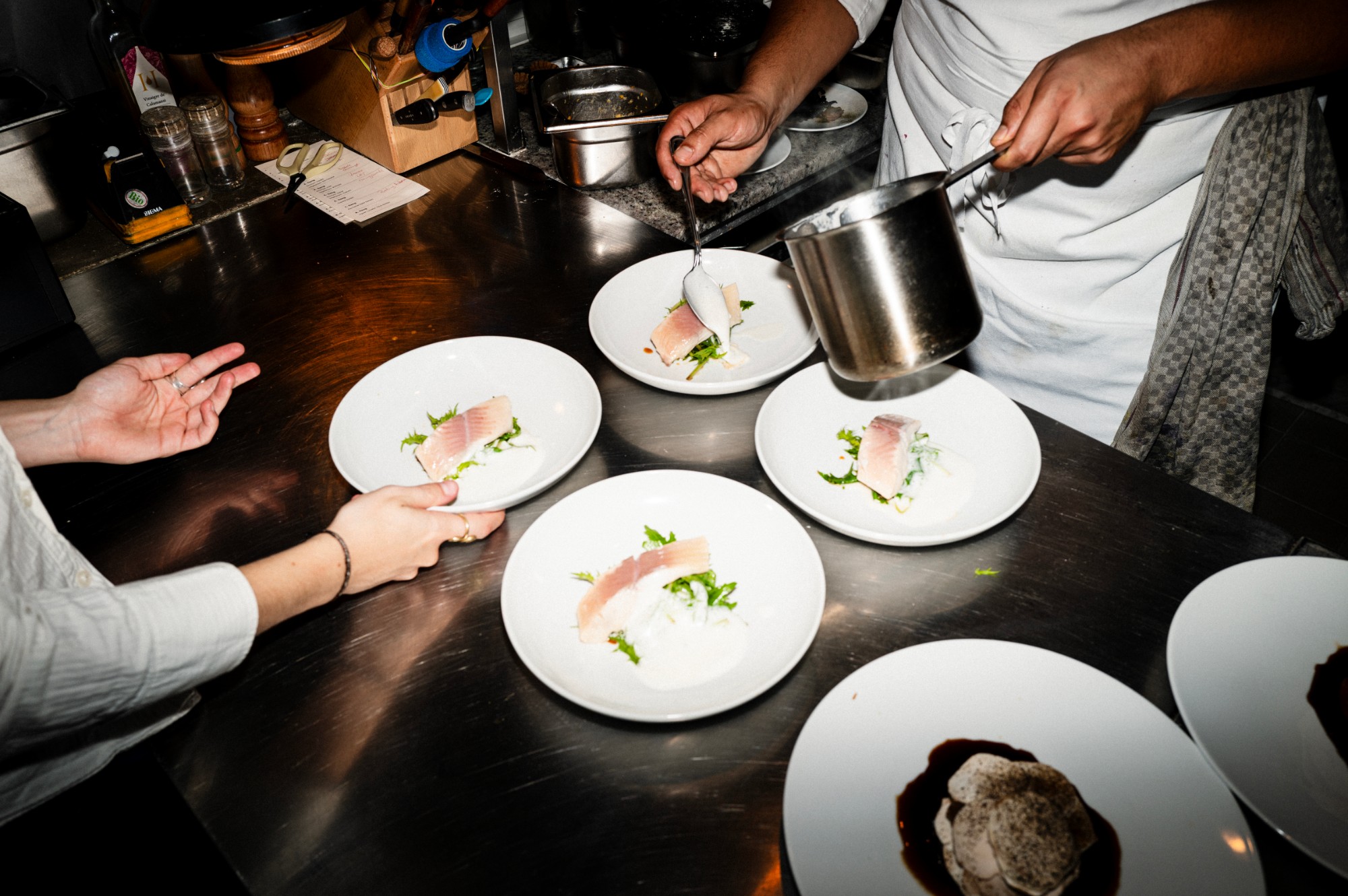 Two plated courses passed across the kitchen counter